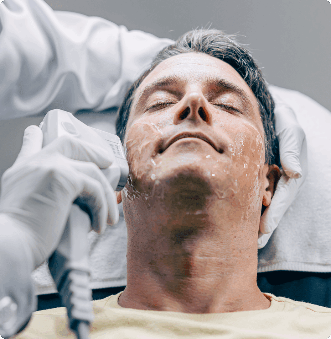 Man receiving facial treatment with handheld device.